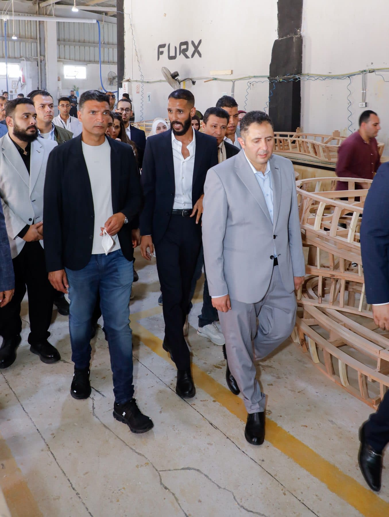 Minister Khaled Hashem and Governor Hossam El-Din Fawzy walk a FURX workshop aisle with Waleed El-Banna, beside raw sofa frames.