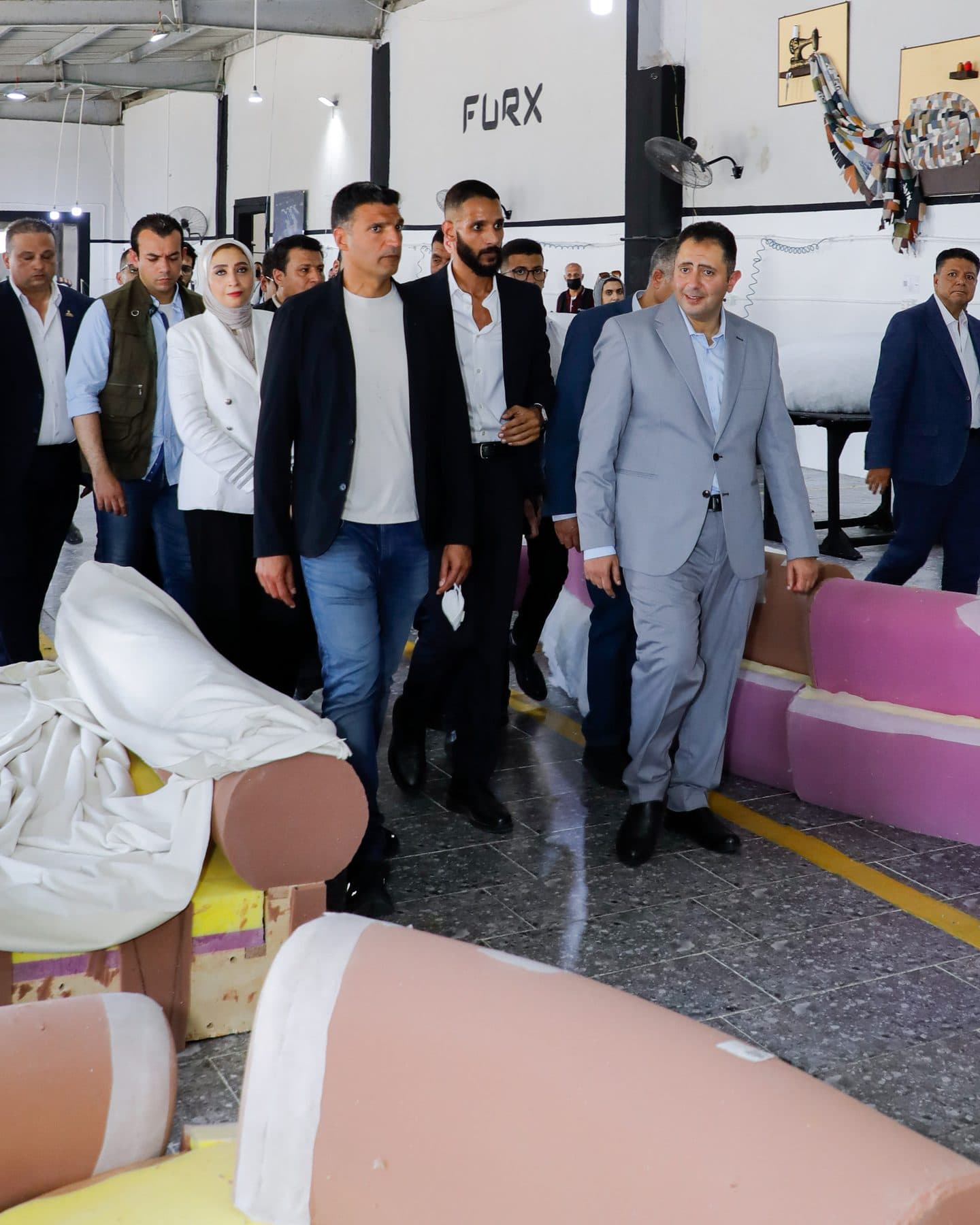 Minister Khaled Hashem, Governor Hossam El-Din Fawzy and Waleed El-Banna walk past foam sofa parts under the FURX wall logo.