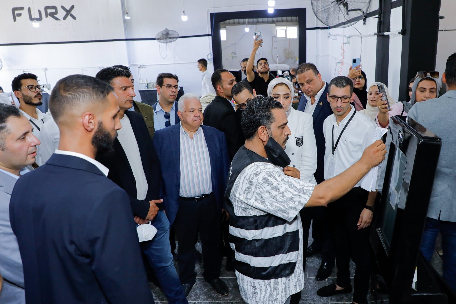 Minister Khaled Hashem watches a FURX technician demonstrate a shop-floor kiosk as the delegation gathers around.