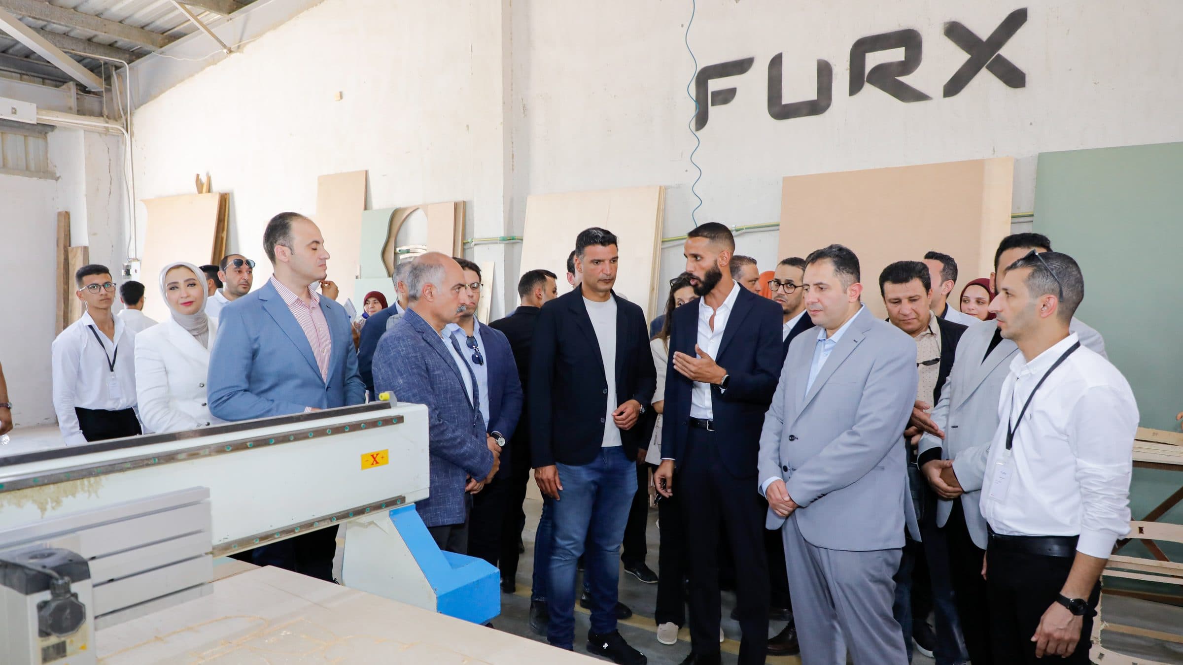 Waleed El-Banna explains with an open hand to Minister Khaled Hashem and Governor Hossam El-Din Fawzy at the CNC router.