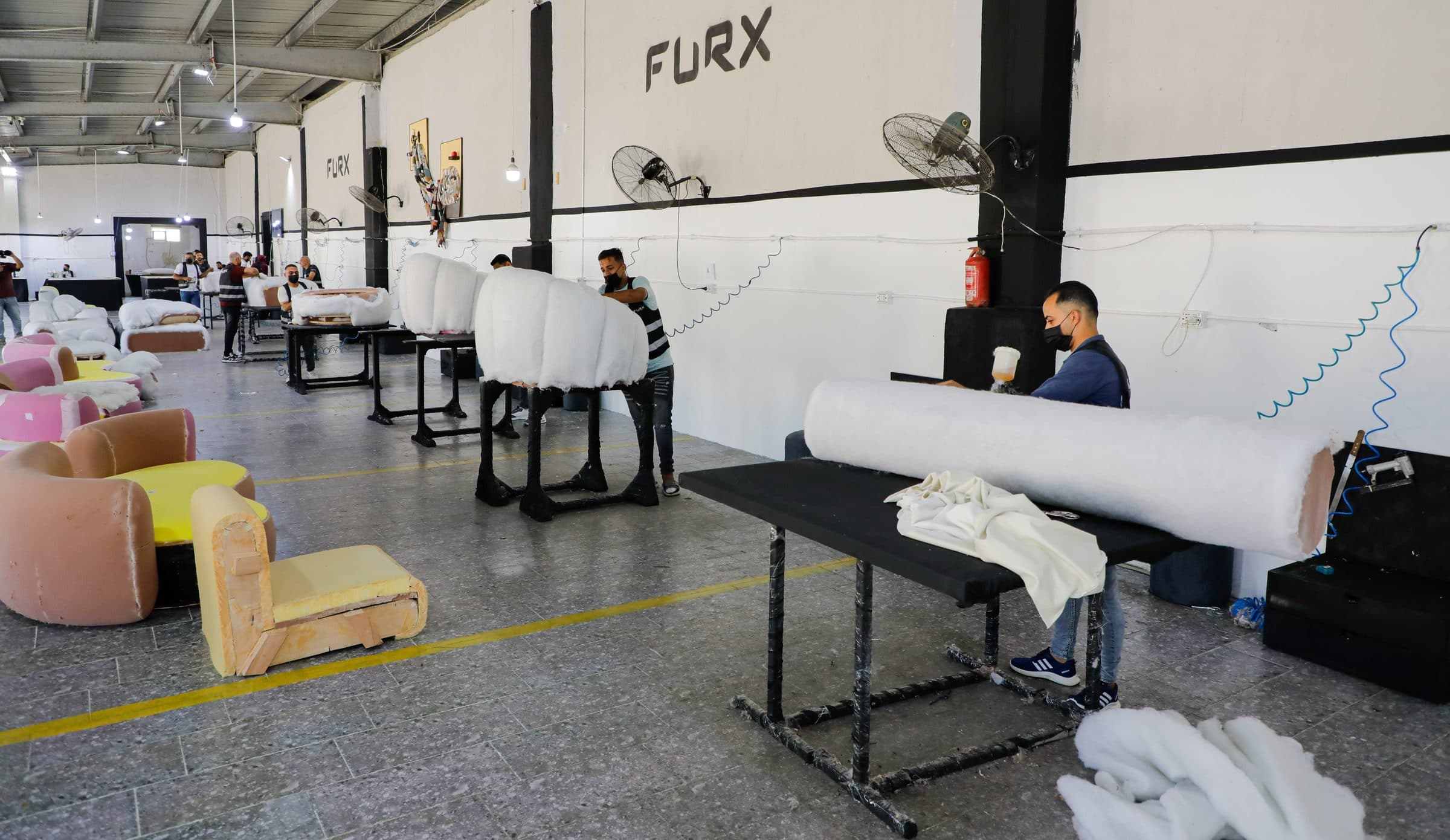 The padding hall: wadded sofa forms on a row of work stands, with foam seat shells in the foreground.