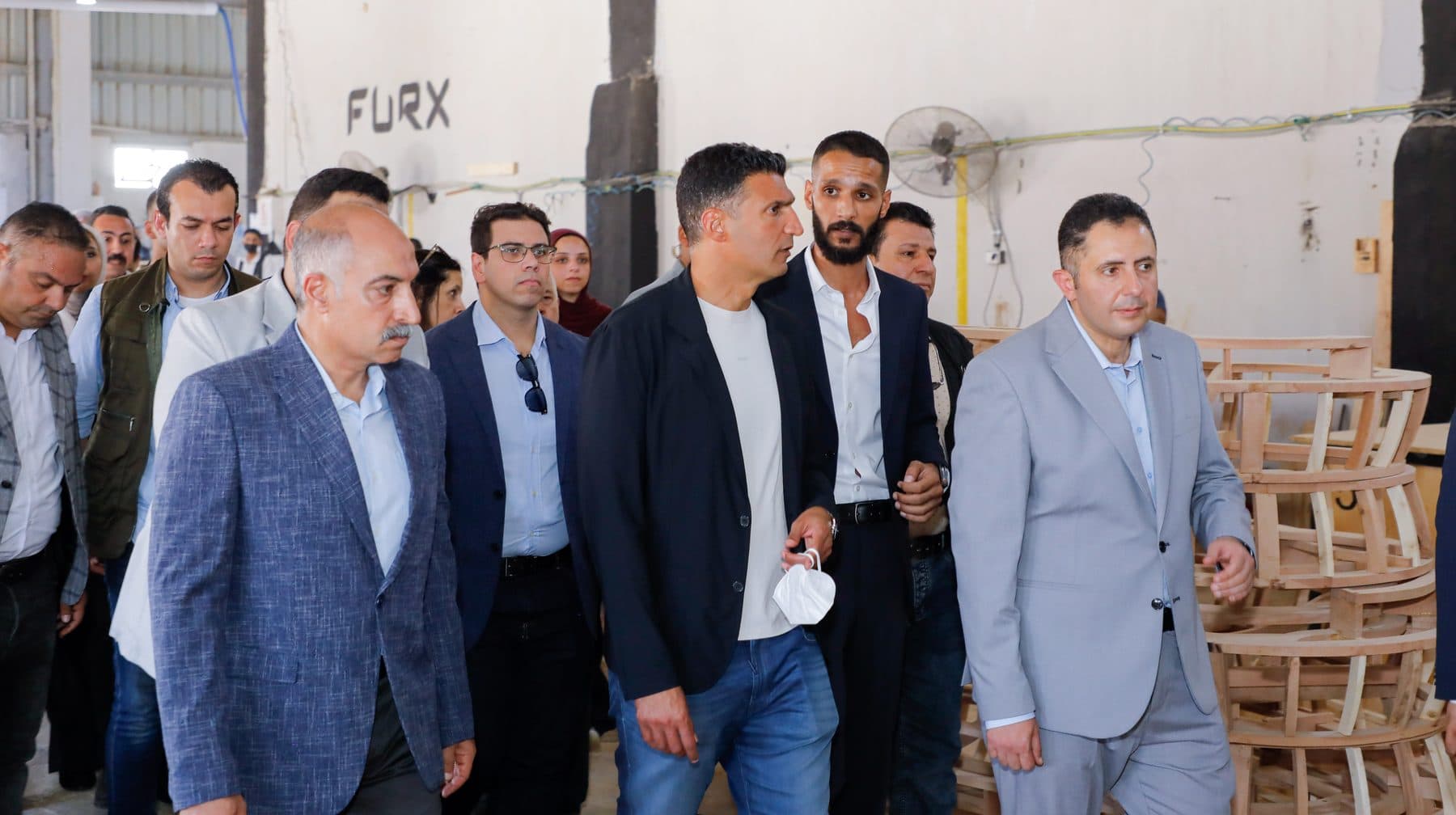 Minister Khaled Hashem talks with FURX founder Waleed El-Banna beside Governor Hossam El-Din Fawzy near stacked chair frames.